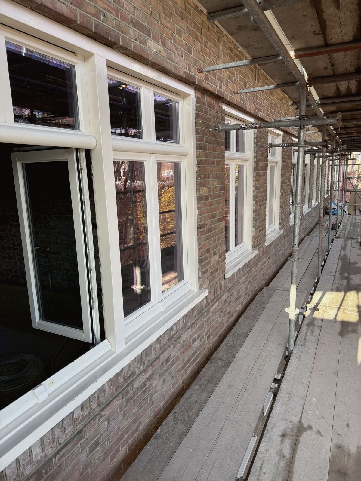 Nieuwe witte kozijnen in een bakstenen gevel in de Rivierenbuurt in Amsterdam, gezien vanaf de steiger.